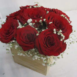 Red roses arranged in a wooden box with white baby's breath
