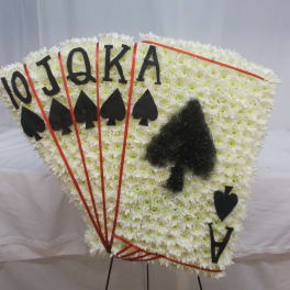 Fan-shaped white floral tribute with playing card symbols and letters