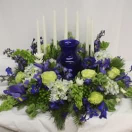 Blue and green floral centerpiece with tall white candles and a cobalt vase
