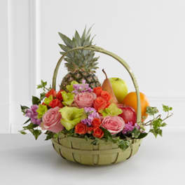 Fruit basket with roses and tropical flowers in a woven basket