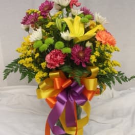 Mixed bouquet in a glass vase with a multicolored ribbon bow