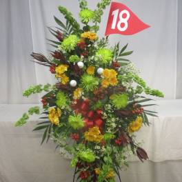 Tall floral standing spray with green and yellow flowers and a red number 18 flag