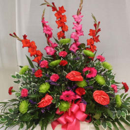 Tall floral spray with red and pink blooms and a bright pink ribbon