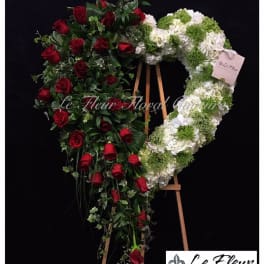 Heart-shaped floral wreath with red roses and white-green blooms on an easel