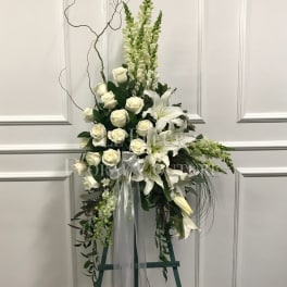 Tall white floral standing spray with roses and lilies on an easel