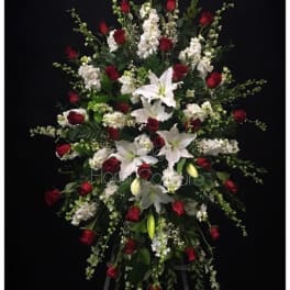 Standing floral spray with red roses and white lilies on a black background