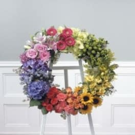 Colorful floral wreath on a stand with mixed blooms in a rainbow gradient