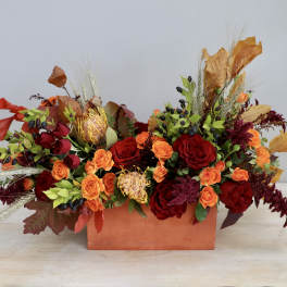 Low arrangement of red and orange roses in a rectangular box