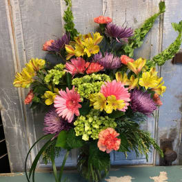 Colorful mixed bouquet in a glass vase with pink, yellow, purple, and coral blooms