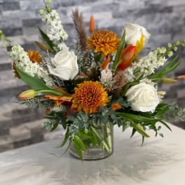 Mixed bouquet of white roses and orange chrysanthemums in a glass vase