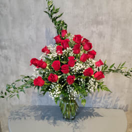 Red roses arranged in a clear glass vase with white baby's breath