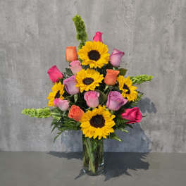 Mixed bouquet of sunflowers and roses in a clear glass vase