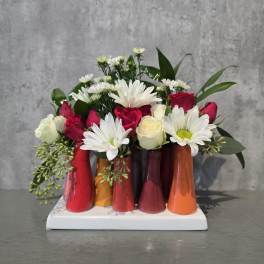Bouquet of red and white roses with white daisies in colorful small vases