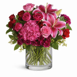 Pink lilies and roses arranged in a clear glass vase