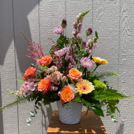 Mixed pink and orange flowers arranged in a white basket vase