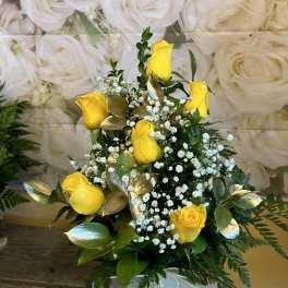 Yellow roses with baby's breath in a clear vase with a white ribbon