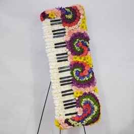 Floral arrangement shaped like a piano keyboard on a stand