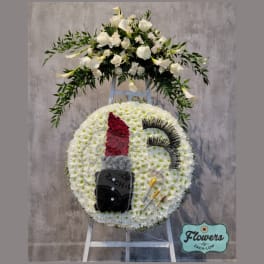Funeral wreath with white flowers and a lipstick design on an easel