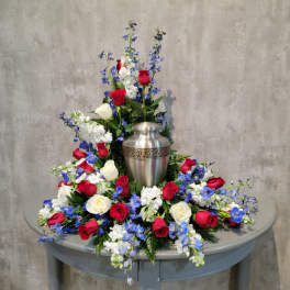 Red, white, and blue floral arrangement around a silver urn