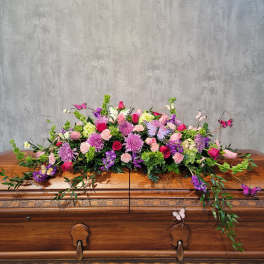 Casket spray of pink, purple, and white flowers with butterfly accents