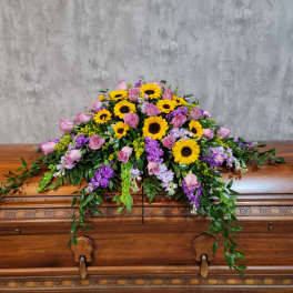 Casket spray with sunflowers, pink roses, and purple flowers