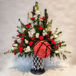 Tall red and white floral arrangement in a black vase with rope netting