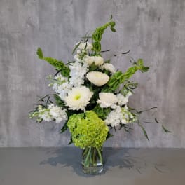 White flowers and green hydrangea in a clear glass vase
