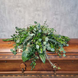 Large greenery spray arranged on a wooden casket