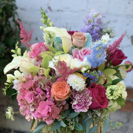 Colorful bouquet with roses, calla lilies, and hydrangeas in a glass vase
