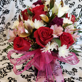 Bouquet of red roses, white lilies, and pink flowers with a pink ribbon
