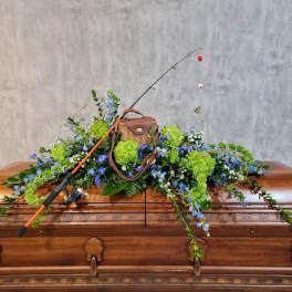Fishing rod resting on a casket with blue and green floral spray