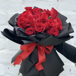 Bouquet of red roses wrapped in black paper with a red ribbon