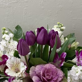 Purple tulips and white flowers with a pink ornamental cabbage