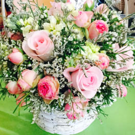 Pink roses and white flowers arranged in a white basket