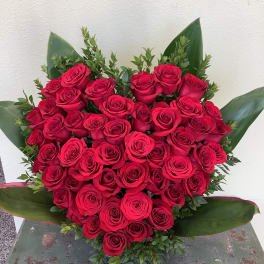 Heart-shaped bouquet of red roses with green foliage