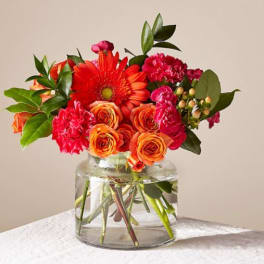 Bright orange and pink mixed bouquet in a clear glass vase