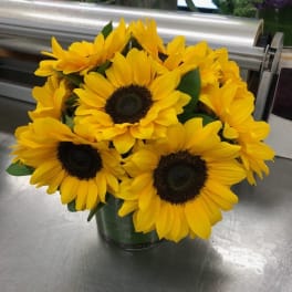 Bouquet of bright yellow sunflowers in a dark vase