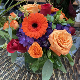 Orange gerbera and roses in a glass vase
