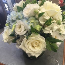 White roses and pale blue hydrangeas in a glass vase