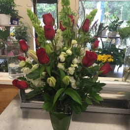 Red roses and white flowers arranged in a glass vase