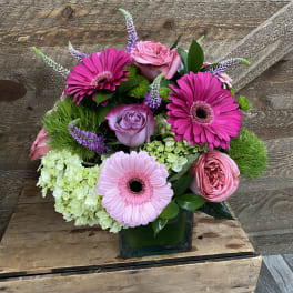Pink and lavender flower arrangement in a square glass vase