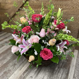 Basket arrangement of pink roses and lilies with greenery