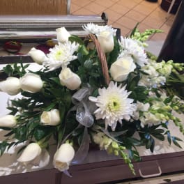 White roses and daisies arranged with greenery in a basket