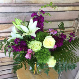 Bouquet of white lilies, pale roses, and purple flowers in a vase