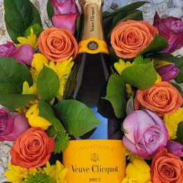 Champagne bottle surrounded by roses and yellow daisies