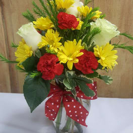 Bouquet of yellow daisies, red carnations, and white roses in a glass vase