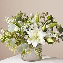 White lilies and green buds in a clear glass vase