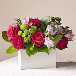 Pink and magenta flower arrangement in a white box