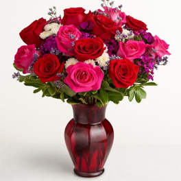 Bouquet of red and pink roses in a red glass vase