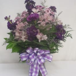 Purple and pink mixed bouquet in a glass vase with a checkered ribbon